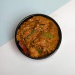 Ajurwedyjskie curry warzywne z przyprawami w czarnej misce z góry