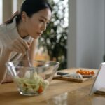 Azjatka przygotowuje sałatkę, śledząc dietetyczny przepis na tablecie