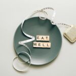 Napis eat well z płytek na talerzu z miarką krawiecką, zdrowe odżywianie