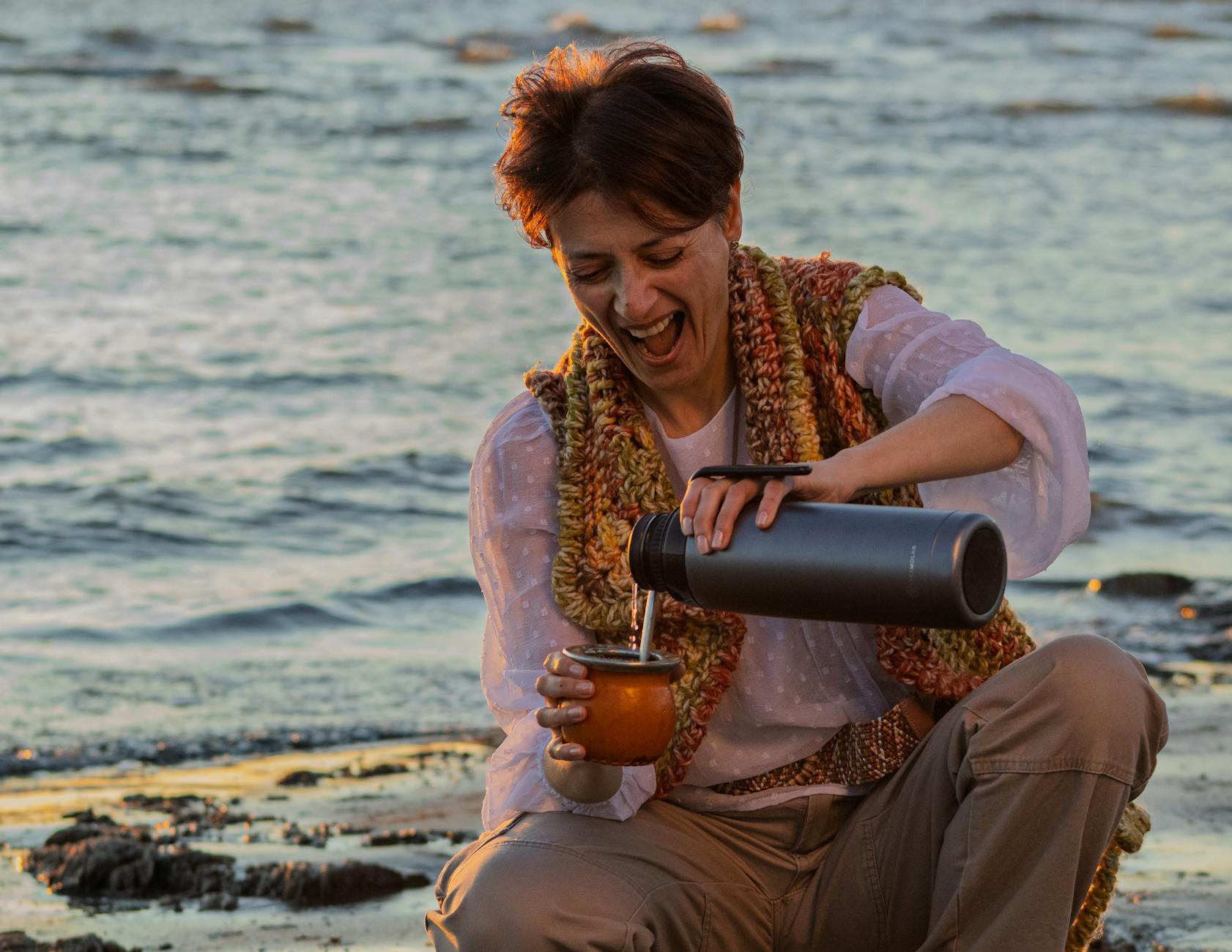 Kobieta pijąca yerba mate na plaży o zachodzie słońca