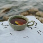 Filiżanka ziołowej herbaty z cytryną nad spokojnym jeziorem