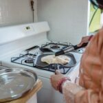 Kobieta smaży ajurwedyjski chlebek z patelni w domowej kuchni