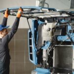 Mechanik w kombinezonie sprawdza silnik ciężarówki w warsztacie