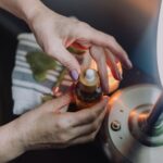 Dłonie trzymają butelkę kosmetyku w ciepłym świetle lampy