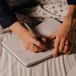 Zbliżenie na dłonie piszące wieczorem w dzienniku przy ciepłym świetle