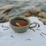 Ceramiczna filiżanka herbaty z cytryną na koronce nad jeziorem