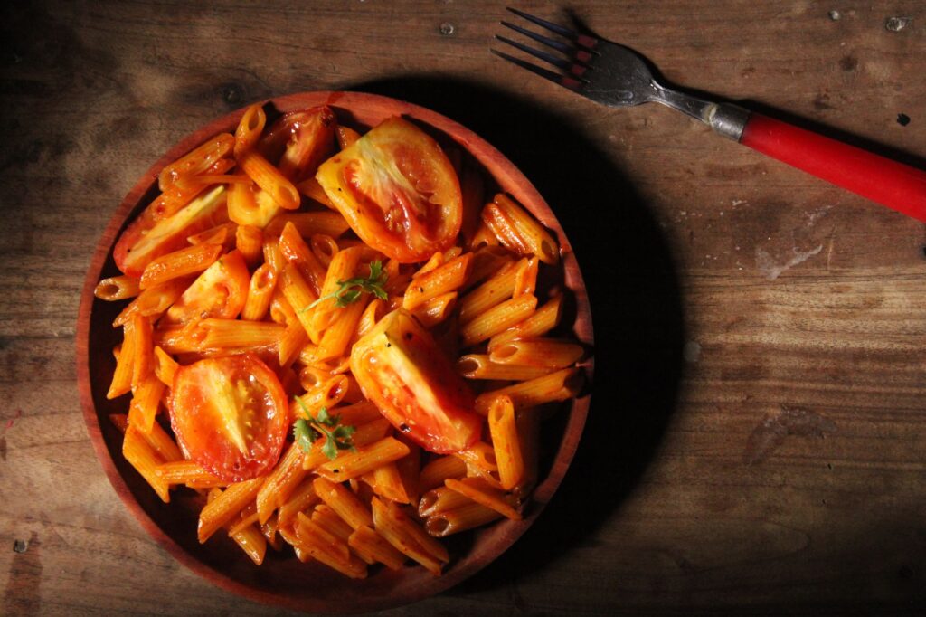 Penne z plasterkami pomidorów na rustykalnym drewnianym stole